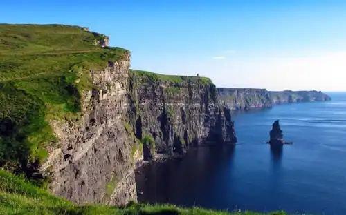 A stunning view of the dramatic, towering Cliffs of Moher dropping steeply into the blue Atlantic Ocean.