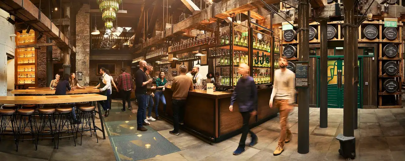 People mingling and enjoying drinks inside the stylish JJ's Bar at the Jameson Distillery.