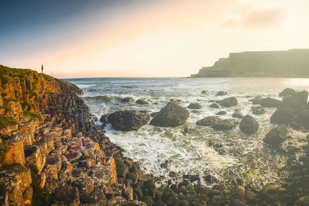 Tourists exploring the massive, interlocking hexagonal stone columns of the Giant's Causeway in Northern Ireland.