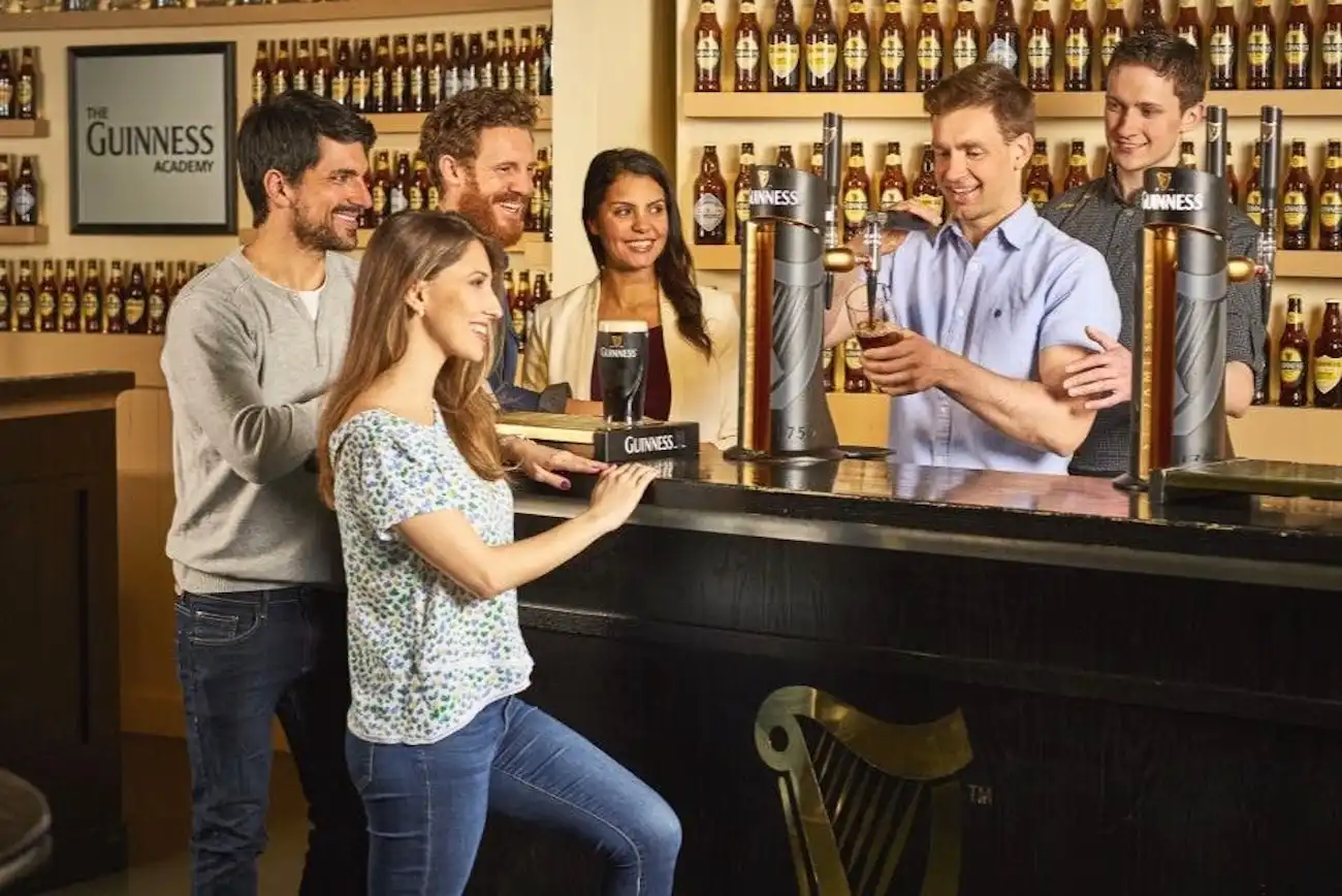 A group of friends laughing while learning how to pour the perfect pint at the Guinness Academy.
