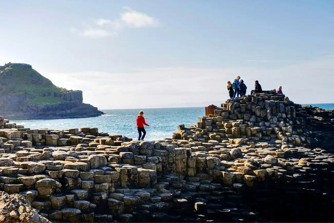 The dramatic, medieval ruins of Dunluce Castle perched precariously on a crumbling cliff edge over the ocean.